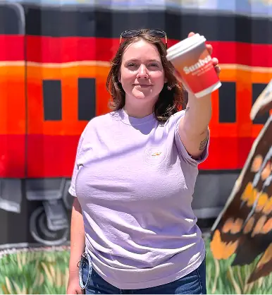 Woman smiling and holding a red fuoco cup out towards the camera