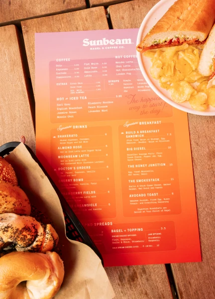 Fuoco menu sitting on a wooden table with bagels and sandwiches sitting next to it