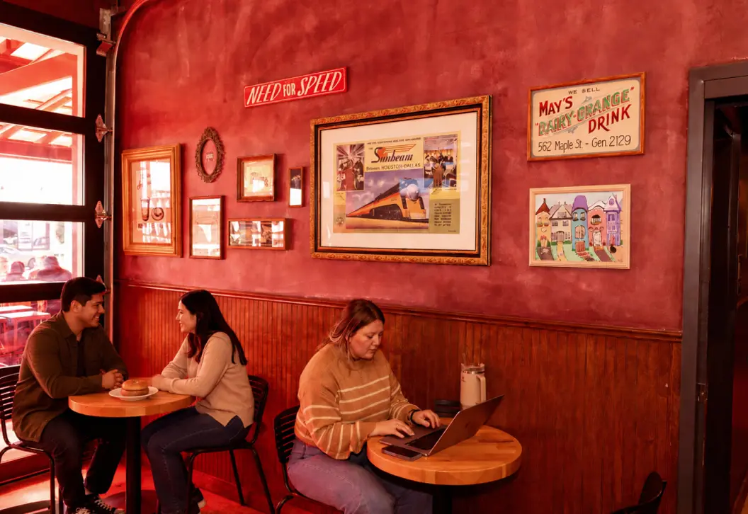Inside of Fuoco Restaurant & Coffee Co. with patrons sitting at tables eating bagels and working on a laptop