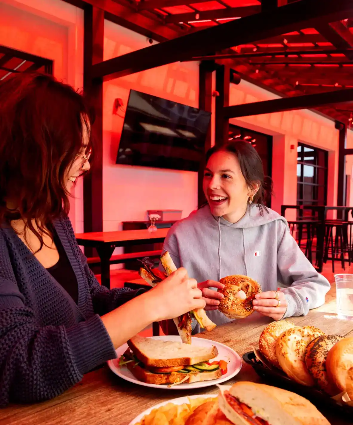 Two women sitting on the patio of Fuoco eating sandwiches and bagels